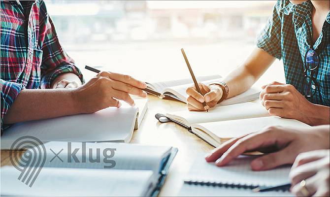 Abgebildet ist ein Tisch, der von mehreren Studierenden als Arbeitsfläche verwendet wird. Bücher und Hefte liegen offen herum.