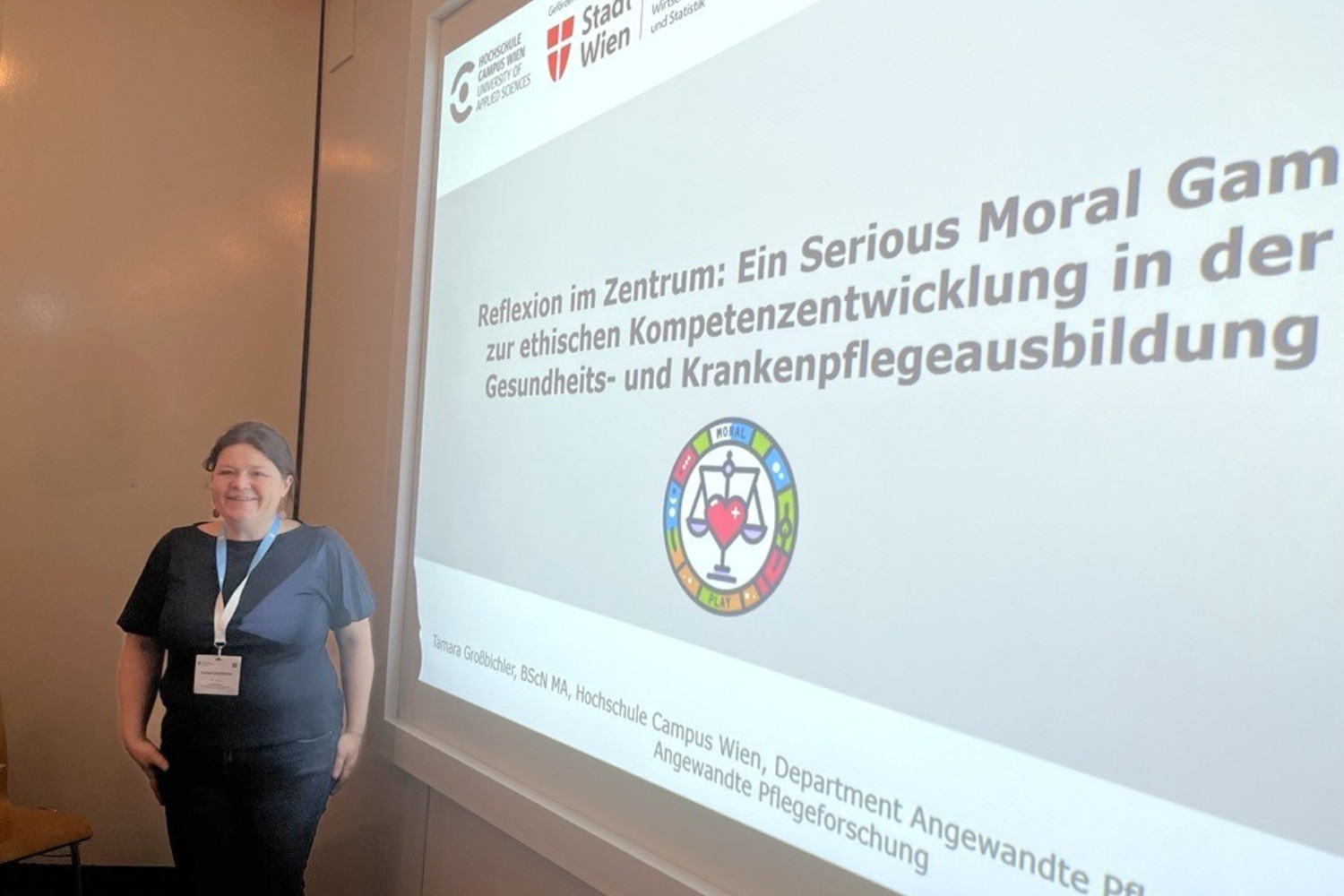 Eine Frau vor einer projezierten Präsentation mit dem Titel Serious Moral Game