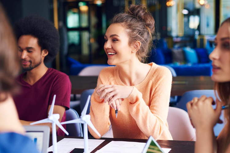 Junge Studierende sitzen zusammen, lernen und arbeiten an einem Projekt.